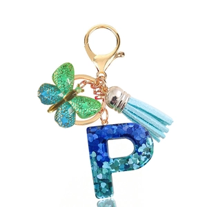 Detail of resin letter P keychain with blue sequins, butterfly charm and blue tassel