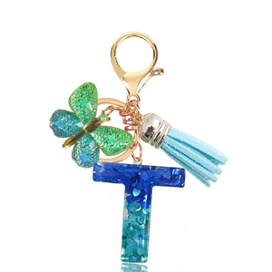 Close-up of letter T resin keychain with blue sequins, butterfly charm, and blue tassel