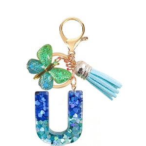 Detail of resin letter U keychain with blue heart sequins, green butterfly, and tassel
