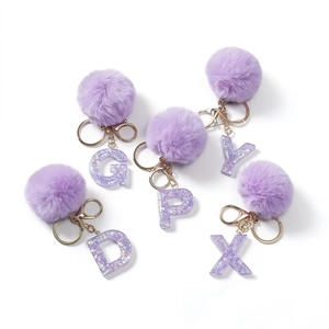 Portachiavi con lettere in resina glitterata viola e morbidi pompon in pelliccia