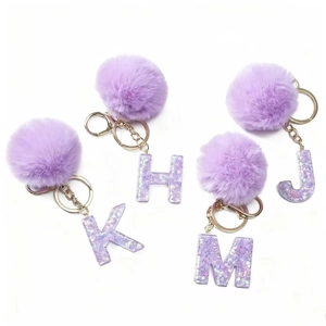 Portachiavi con pompon in ecopelliccia viola e lettere dell'alfabeto in resina H J K M