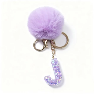 Dettaglio del portachiavi lettera J in resina viola con glitter e pompon in finta pelliccia