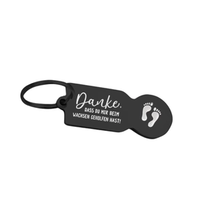 Close-up of black stainless steel shopping trolley token keychain with German laser engraving