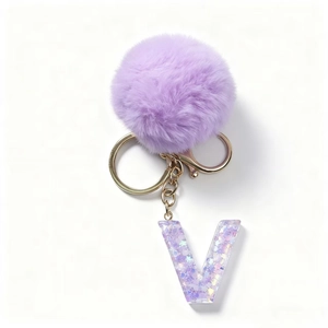 Dettaglio del pompon in pelliccia viola e portachiavi con lettera V in resina e gancio oro