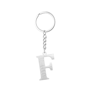 Macro shot of silver stainless steel letter F keychain with brushed metal texture