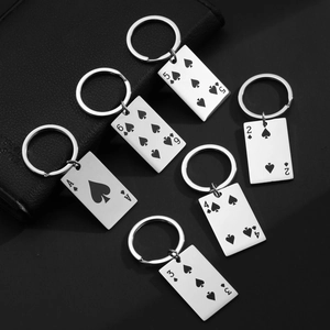 Detail shot of stainless steel poker Ace cards keychains set on black leather background