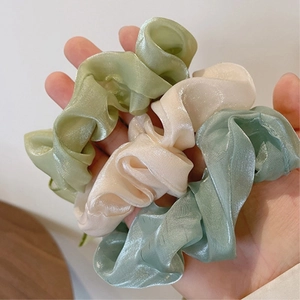 Dettaglio di tre elastici per capelli in organza lucida nei colori verde, giallo e blu