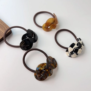 Close-up of four acetate hair ties in amber, black, checkered, and tortoiseshell patterns