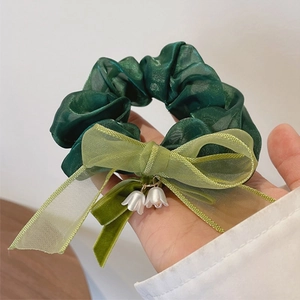 Dettaglio dell'elastico in organza verde con fiocco e pendenti di mughetto