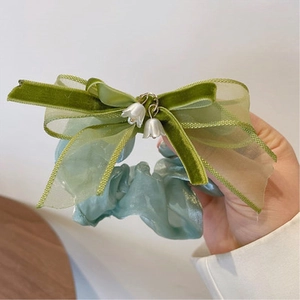 Dettaglio di ciondoli mughetto su elastico blu con fiocco in velluto verde