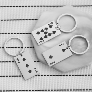 Stainless steel poker card keychains featuring Ace of Spades on white marble tray