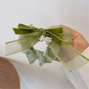 Dettaglio dello scrunchie verde con mughetto, fiocco di velluto e ciondoli a perla