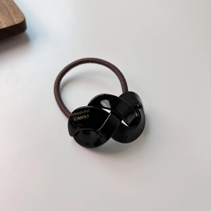 Detailed macro view of black resin twist knot accessory with France Handmade gold text