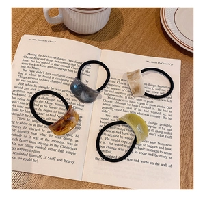 Detailed close-up of high elasticity hair ties with acetate marble texture charms on book