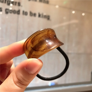 Detail of high-elastic black hair tie with amber marble resin link accent shown in hand