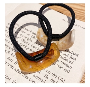 Detail of high-elasticity hair ties with amber and cream acrylic moon-shaped charms