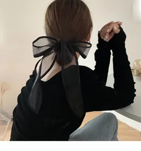 Detail of elegant black organza bow hair scrunchie with long ribbons on model