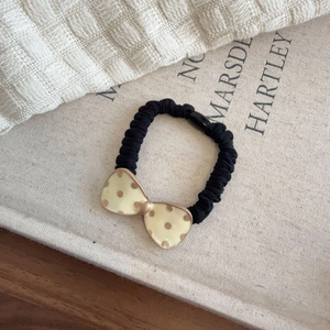 Cute polka dot bow scrunchie with high-elastic black pleated hair tie on a book