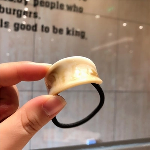 Minimalist elastic hair tie with amber marble resin detail shown in close-up view