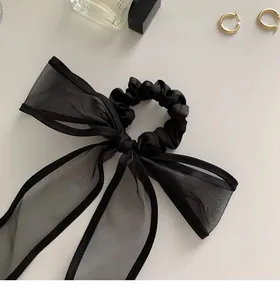 Detail of elegant black mesh bow scrunchie with satin band and sophisticated mesh texture