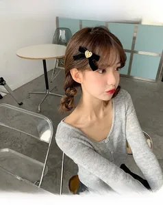 Détail d'une pince à cheveux nœud en velours noir avec un cœur doré sur le côté
