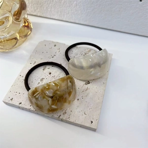 Detail of marble pattern acetate hair ties in pearl white and amber brown colors