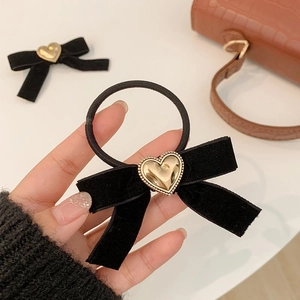 Détail d'un chouchou en velours noir orné d'une boucle métallique en forme de cœur doré