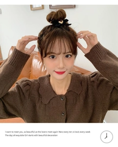 Détail d'un chouchou à nœud noir avec boucle cœur dorée sur les cheveux d'un mannequin
