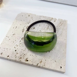 Detailed macro view of a green translucent resin hair tie on a white stone background
