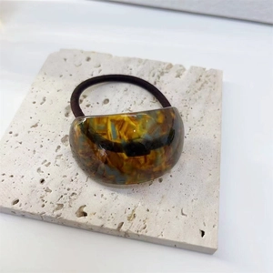 Close-up of amber texture acetate hair tie on a white marble display board