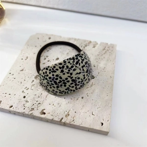Close-up of polished black and white spotted acetate plate on high elastic hair tie
