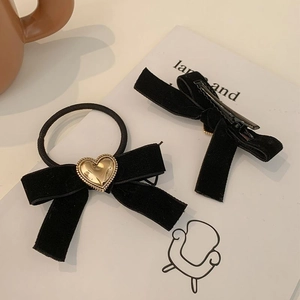 Détail de nœuds de cheveux en velours noir avec breloques cœur dorées sur carte décorative