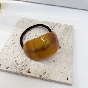 Close-up of elegant amber acetate hair tie with high-elastic black rubber on travertine