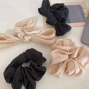 Detail of satin scrunchies with pleats and bows in champagne and black silk-like fabric