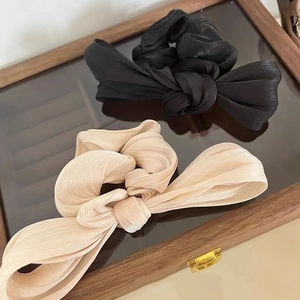 Detailed view of large satin bow hair ties in black and champagne on a wooden box