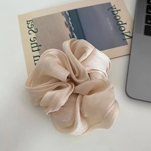Close-up of champagne satin scrunchie with soft pearl texture and pleated fabric detail
