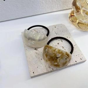 Elegant tortoiseshell and pearl white acetate hair rings on a stone display stand