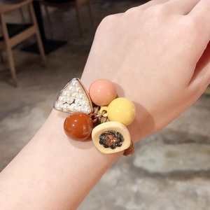 Élastique à cheveux perles colorées et triangle avec charms floraux porté au poignet