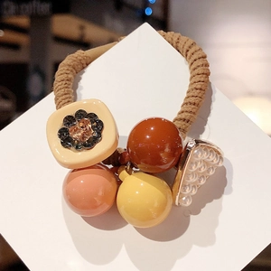 Détail d'un élastique à cheveux vintage avec triangle en perles et breloques en résine
