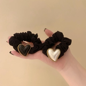 Close-up of black scrunchies with metallic heart charms in pearl white and mirror black