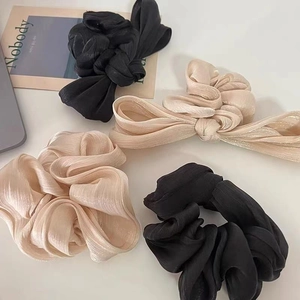 Elegant satin bow scrunchies in champagne and black featuring a soft pleated texture