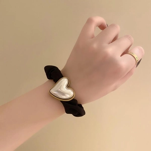 Elegant black scrunchie with a large pearl heart pendant worn on the wrist