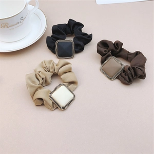 Three satin hair scrunchies in black, brown, and beige with square vintage charms