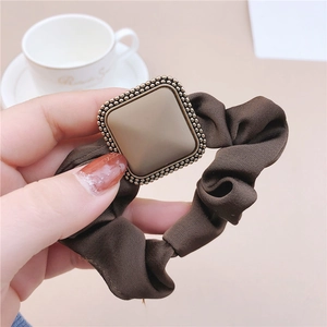 Close-up of vintage brown scrunchie with a gold square buckle and textured fabric