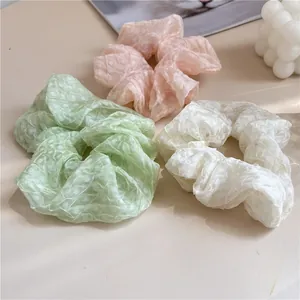 Détail de trois chouchous en organza pastel avec texture à pois et volants doux