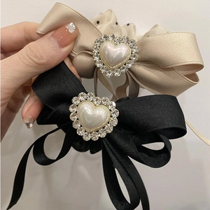 Detailed view of satin bow hair ties with heart-shaped pearls and rhinestone embellishments