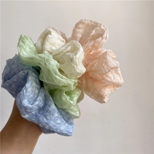 Gros plan d'un lot de chouchous aux couleurs pastel bleu, vert, beige et rose doux