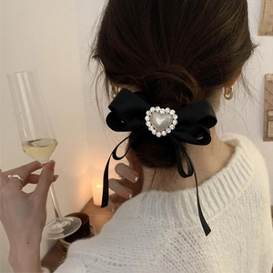 Detail of a black silk bow hair clip with heart pearl and rhinestone centerpiece