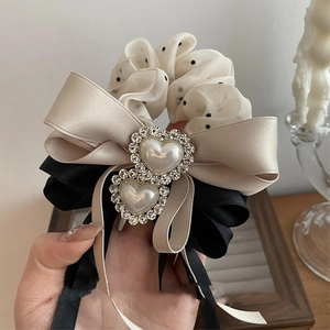 Close-up of a satin bow hair tie with pearl hearts and rhinestone embellishments