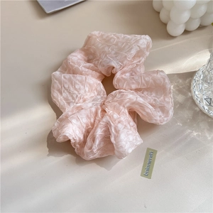 Gros plan d'un chouchou rose clair en organza plissé pour une coiffure élégante